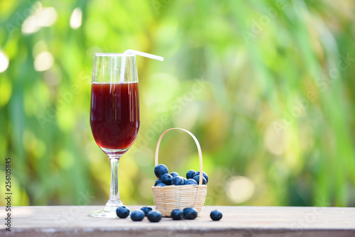 Blueberry smoothie juice glass and fresh blueberries fruit in basket with nature green summer background