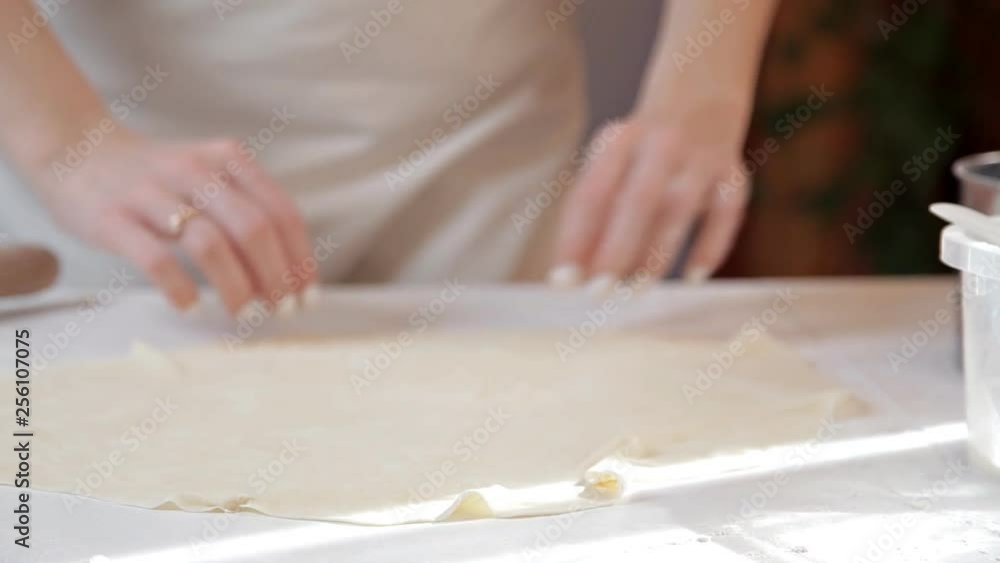 The girl smooths the dough with her hands on the table, making sure that it is even The girl smooths the dough with her hands on the table, making sure that it is even