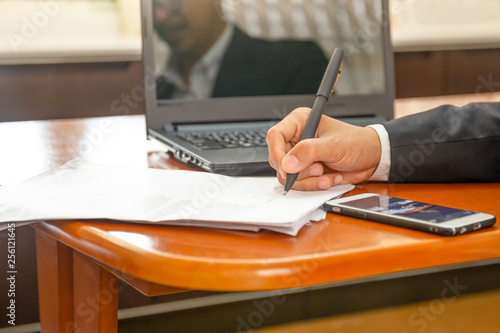 Businessman working on laptop and writing on paper notebook. photo