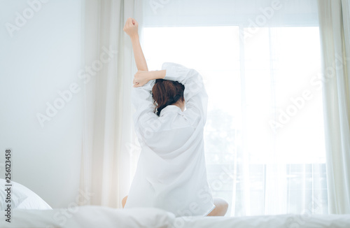 Woman wake up rear view at moring her stretch on bed at home.