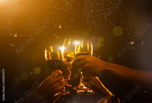 Clink Glasses at night party celebration friends group golden tone, Hands holding wine for event festival. photo