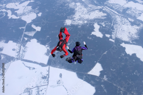 The team of two skydivers is training in the sky.