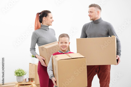 Young family, man woman and child son in new apartments. Carried in the hands of cardboard boxes. Boxes with cargo on a white background.