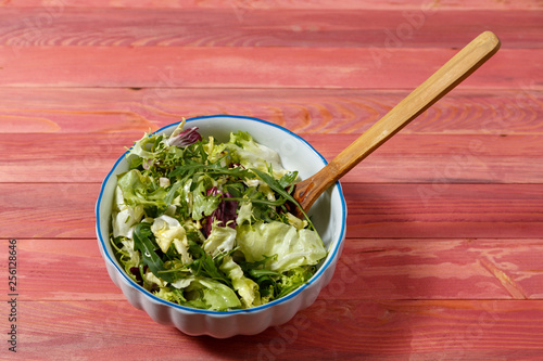 Fresh vegetarian salad from escariol, frieze, radicio, arugula in a white plate on a wooden background. photo