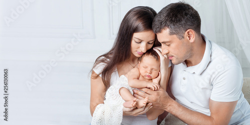 Woman and man holding a newborn. Mom, dad and baby.  Portrait of  smiling family with newborn on the hands. Happy family concept. Copy space