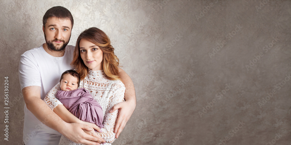 Woman and man holding a newborn. Mom, dad and baby.  Portrait of  smiling family with newborn on the hands. Happy family concept. Copy space