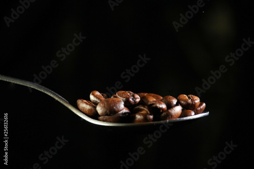 A spoon with coffee beans at dark background