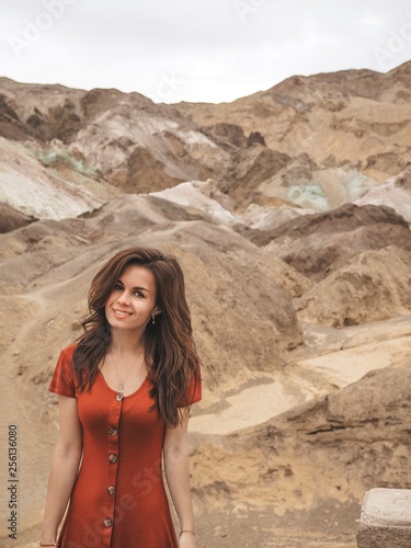 A girl with long hair in a red dress on the background of Color mountains of Death valley.