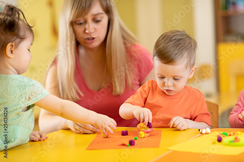 Little kids molded from clay toys. Teacher or mom play with children.