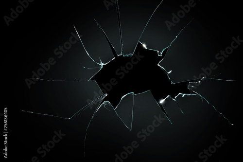 Foto broken cracked glass with big hole over black background