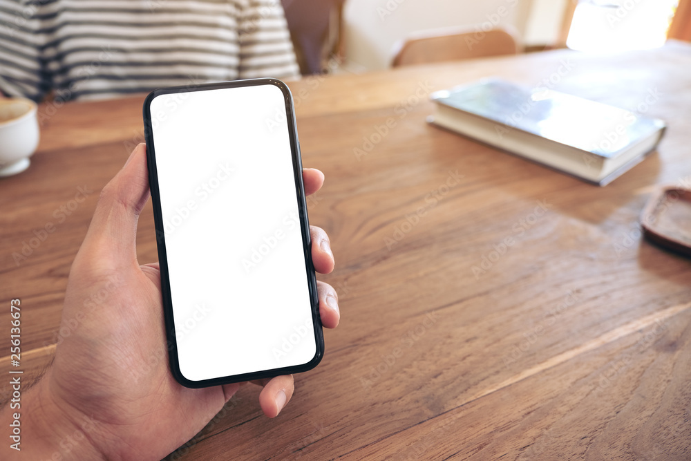 Mockup image of a man's hand holding black mobile phone with blank screen with woman in cafe Mockup image of a man's hand holding black mobile phone with blank screen with woman in cafe