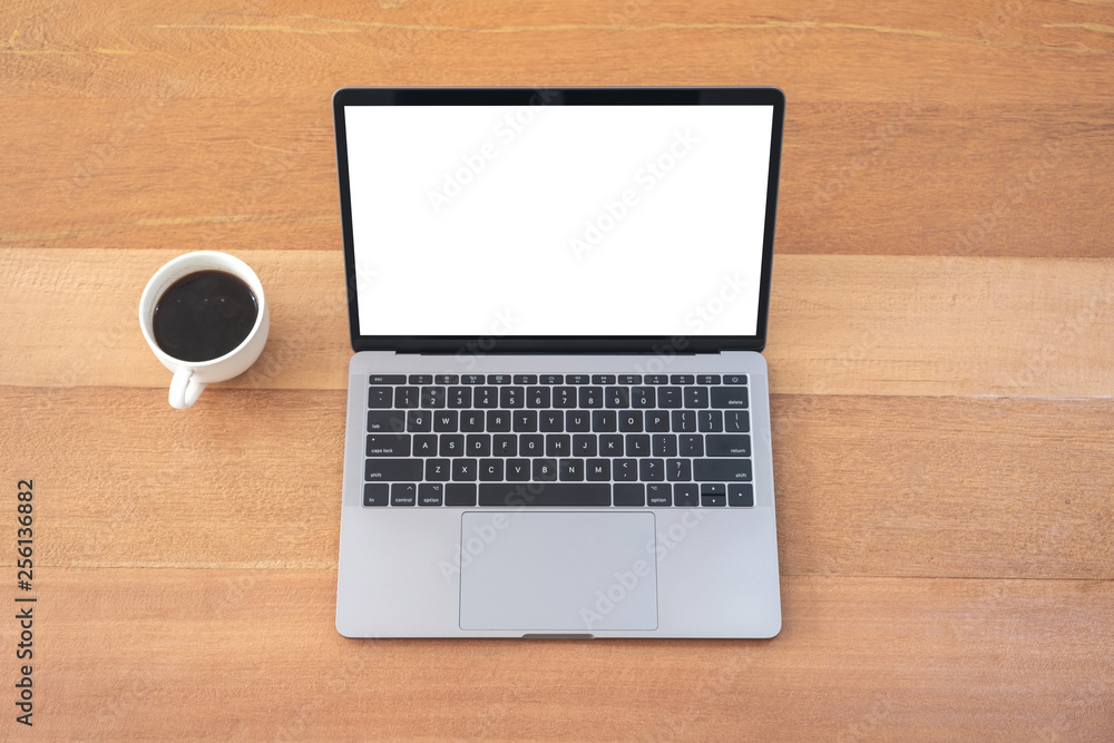 Top view mockup image of laptop with blank white desktop screen with coffee cup on wooden table Top view mockup image of laptop with blank white desktop screen with coffee cup on wooden table