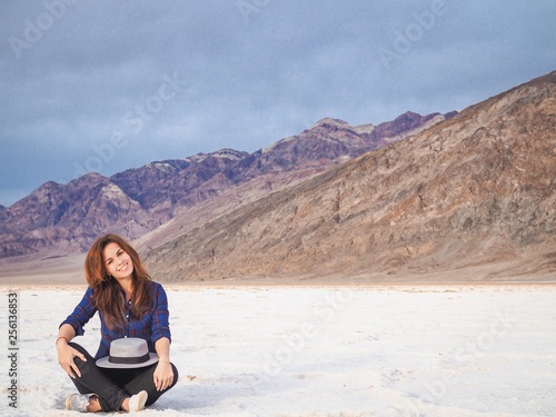 Brunette girl in a plaid shirt with long hair holding a hat on saline soil Badwater in Death Valley © KseniaJoyg