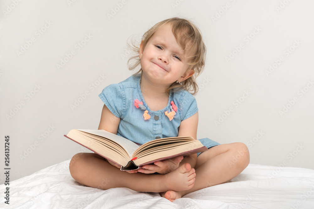 Cute little child in blue dress reading a book Cute little child in blue dress reading a book