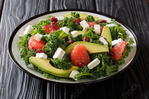 Organic kale salad with avocado, grapefruit, feta and dried cranberries with lemon dressing close-up on a plate on a table. horizontal