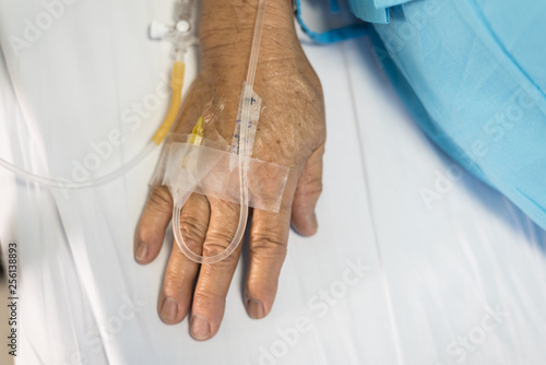 Tableau sur toile Close up old woman patient hand and iv set for fluid intravenous drop saline drip on white hospital bed background in the hospital room