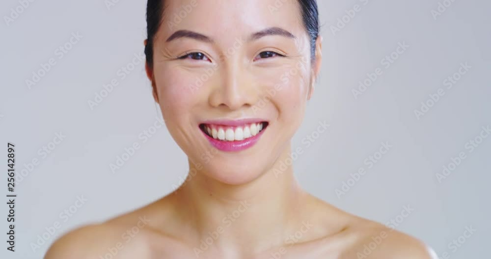 Slow motion of asian woman with beautiful face and perfect skin just cleaned from impurities smiling in camera. Slow motion of asian woman with beautiful face and perfect skin just cleaned from impurities smiling in camera.