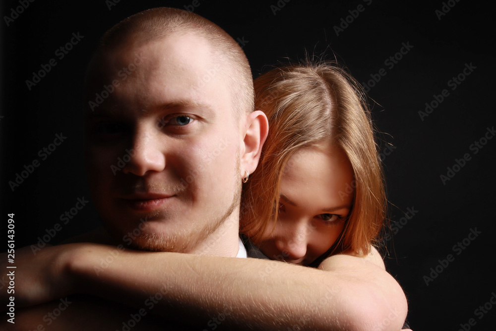 Fototapeta premium Young woman hugs her beloved man from behind