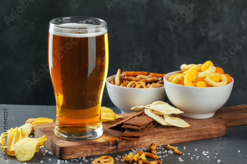 Glass of lager beer with snack bowls on dark stone background photo