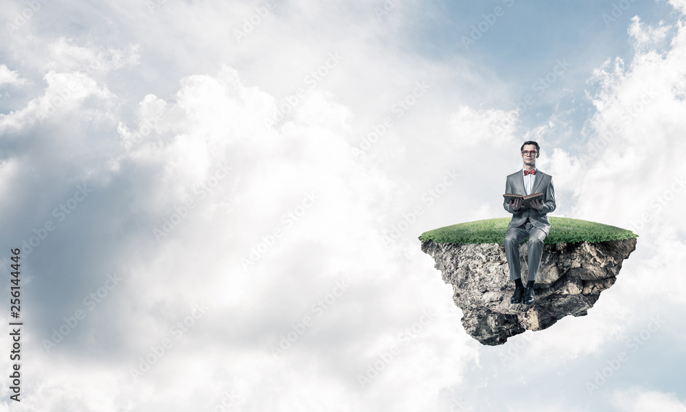 Young businessman or student floating in sky and studying the science Young businessman or student floating in sky and studying the science