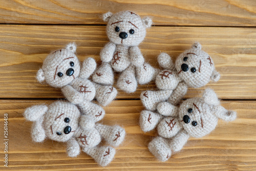A knitted beige bunnies and bears are lying on the wooden floor