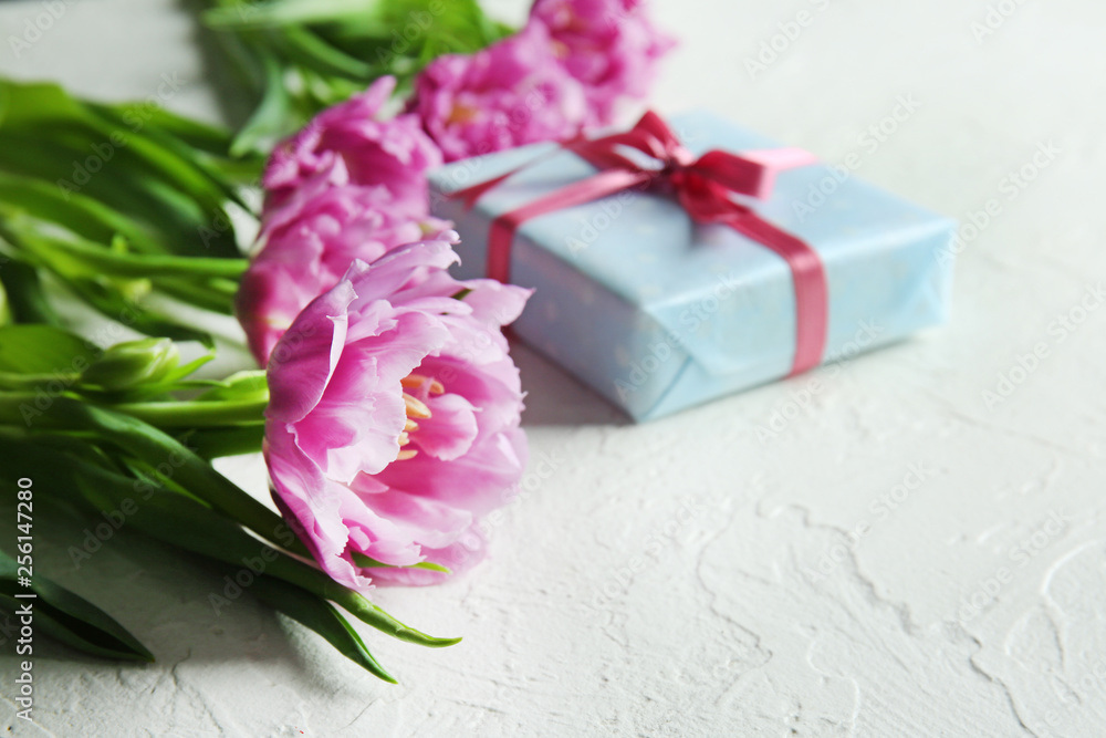Gift box with beautiful tulips on white textured background Gift box with beautiful tulips on white textured background