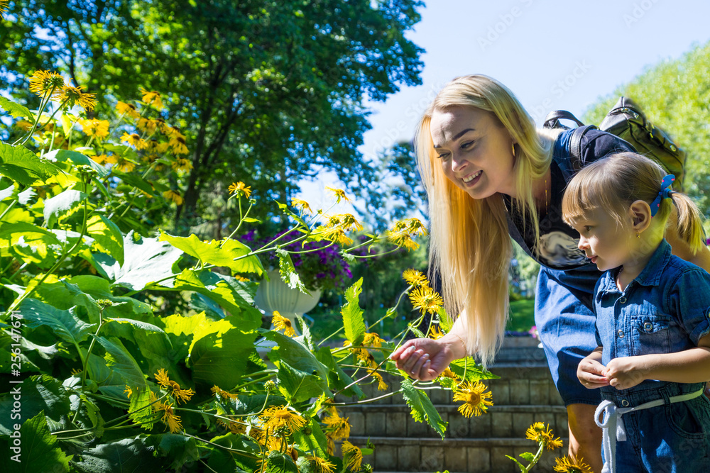 Cute blonde woman and her daughter in the park - obrazy, fototapety, plakaty 