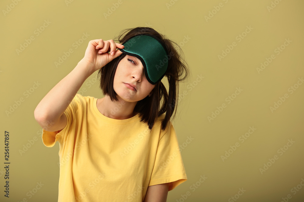 Sleepy young woman with mask on color background Sleepy young woman with mask on color background
