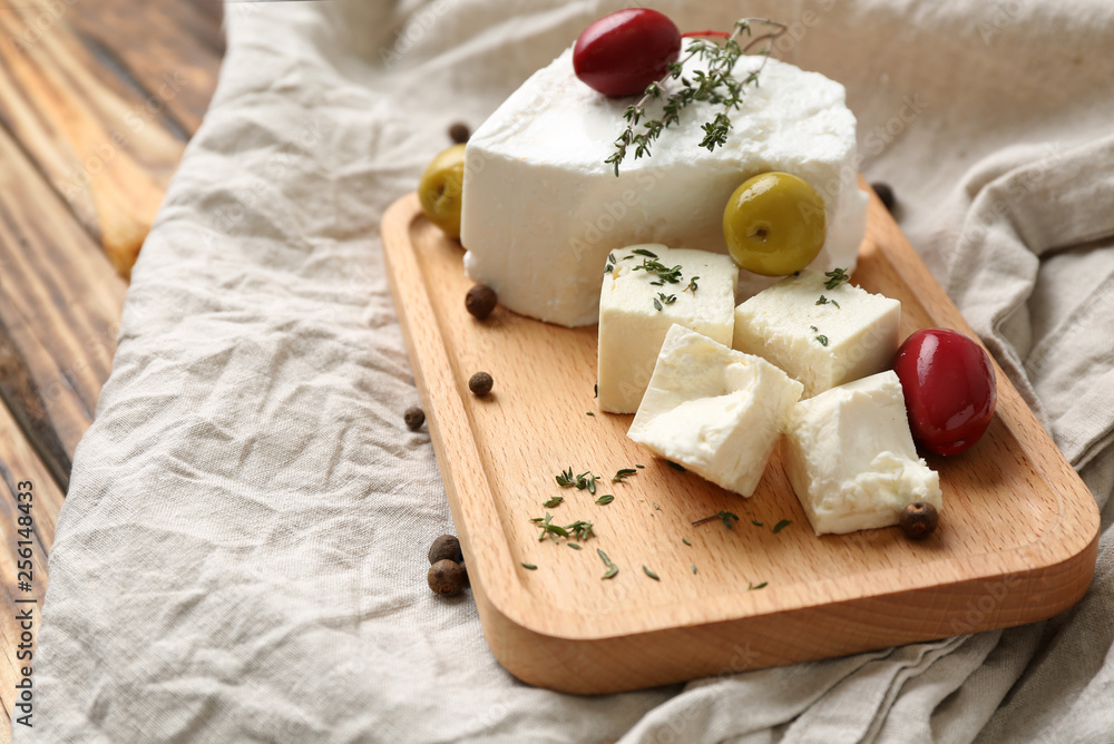 Board with tasty feta cheese and olives on table