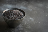 Black rice in bowl on black background. Copy space.