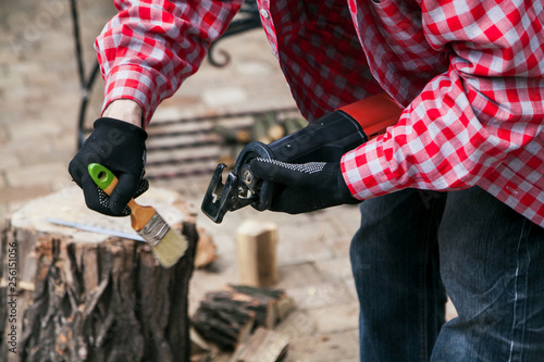 Hands in gloves clean electric saw with brush close-up