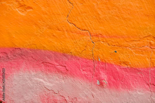 Colorful Graffiti texture on wall as background. Closeup with detail Colorful  red orange and sprayed graffiti on aged cracked brick wall with drips, smears and peeling paint
