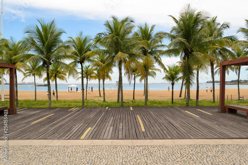 The seafront of the nice city of Vitoria, Espirito Santo in Brazil. A wooden deck and some palm trees just in front of the beach photo