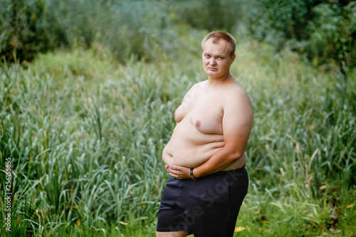 Obraz na plátně a very fat guy without a shirt is standing in the park