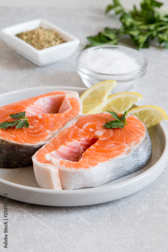 fresh fish. fresh salmon steaks with lemon, spices and salt in a light plate fresh fish. fresh salmon steaks with lemon, spices and salt in a light plate