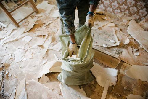 Worker cleans the trash in the apartment in the bag