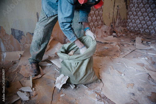 Worker cleans the trash in the apartment in the bag