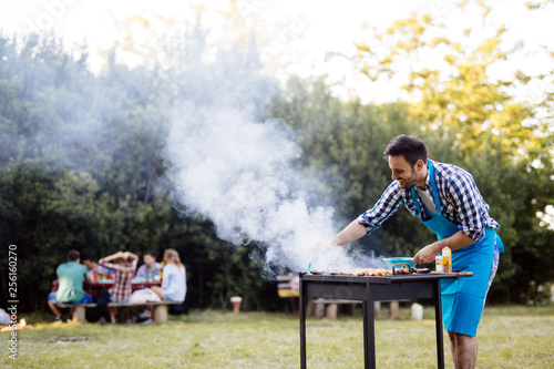 Handsome young male preparing barbecue in nature