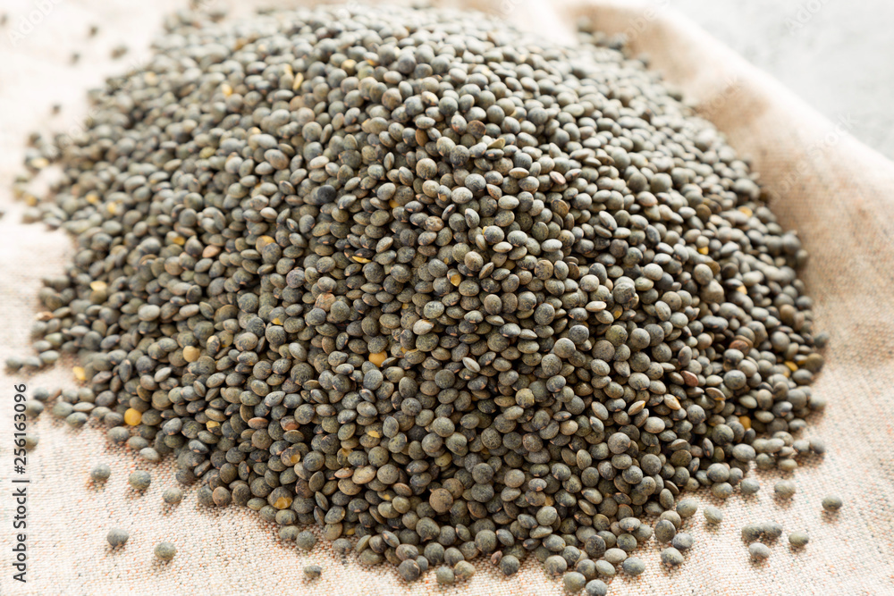 Dry green french lentils on cloth, side view. Close-up. Dry green french lentils on cloth, side view. Close-up.