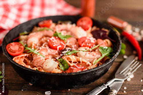 Tasty pasta with shrimp and tomato on a frying pan