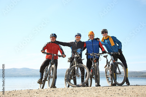 group of cyclists on shore of a mountain lake. team outdoors. mountain bike