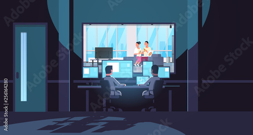 two men looking at monitors behind glass couple eating pizza man woman watching tv relaxing on couch dark office interior surveillance security system flat horizontal