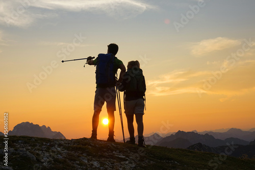 SILHOUETTE Hiker couple watches the scenic sunset after reaching the mountaintop