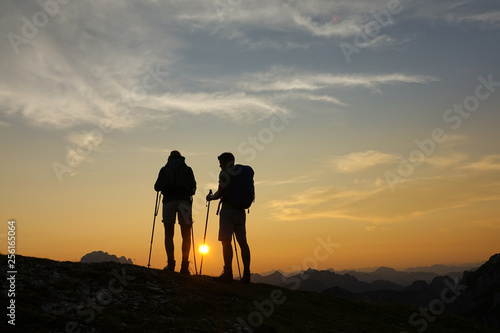 SILHOUETTE: Unrecognizable hikers watch the sunset from a peak in the Alps.