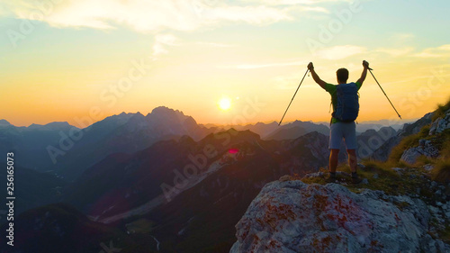 SILHOUETTE: Cheerful male hiker celebrates catching the sunset in the Alps.