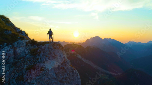 SILHOUETTE: Unrecognizable male tourist hiking in the Alps observing the sunset. © helivideo