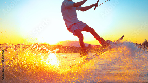 SUN FLARE: Cool surfer dude does 180 ollie while wakeboarding on sunny evening photo