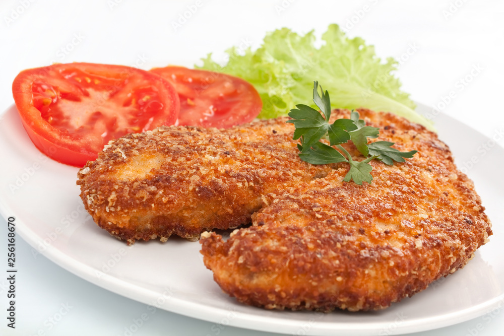 Deep fried chicken parmesan on a white plate with vegetables