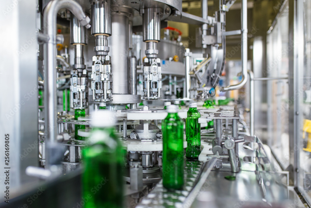 Bottling plant - Water bottling line for processing and bottling pure spring water into green glass bottles. Selective focus. Bottling plant - Water bottling line for processing and bottling pure spring water into green glass bottles. Selective focus.