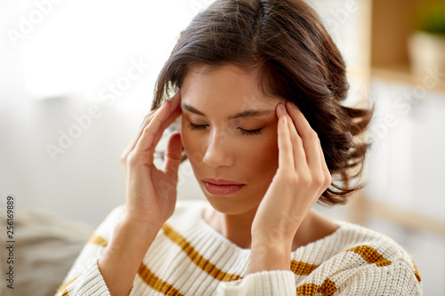 people , health and stress concept - unhappy woman suffering from head ache at home photo